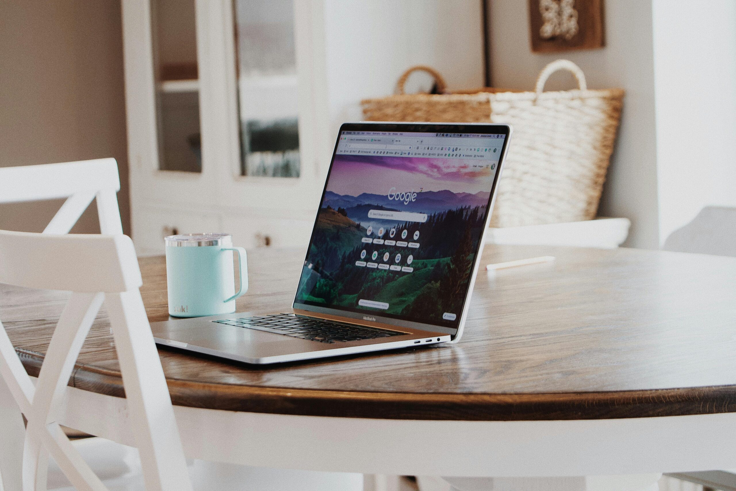 A sleek laptop on a wooden table with a mug, exemplifying a modern home workspace.